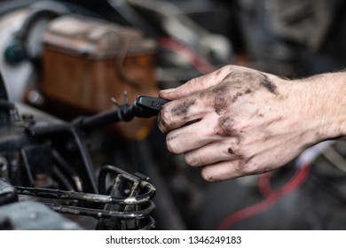 Skilled Mechanic Checking Fluids In An Old Truck By Pulling Out The Dipstick Before A Trip. Safety Check Before Travel. Grease On Hands, Checking Engine Oil And Transmission Fluid. Diesel Motor 