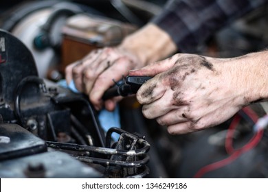 Skilled Mechanic Checking Fluids In An Old Truck By Pulling Out The Dipstick Before A Trip. Safety Check Before Travel. Grease On Hands, Checking Engine Oil And Transmission Fluid. Diesel Motor 