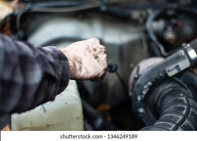 Skilled Mechanic Checking Fluids In An Old Truck By Pulling Out The Dipstick Before A Trip. Safety Check Before Travel. Grease On Hands, Checking Engine Oil And Transmission Fluid. Diesel Motor 