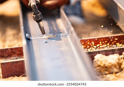 A skilled metalworker using a gas torch to cut through steel. Precision, craftsmanship, and inherent danger of sparks flying in industrial metal fabrication process. Metal fabrication. - Powered by Shutterstock