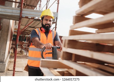 Skilled people working in construction site. Hispanic man at work in new housing project. Professional latino worker using manual pallet jack to move material. - Shutterstock ID 1266017275