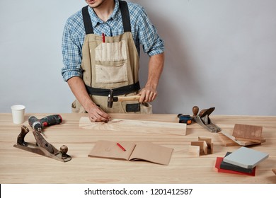 Skilled pleasant craftsman hammering down a nail to wooden plank, engaging in house renovation. - Powered by Shutterstock