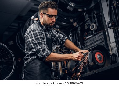 Skilled repairmaster is working with machine tool at busy bucycle workshop.