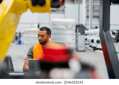 Skilled robotics engineer programming machines in high tech factory with laptop, ensuring efficiency and quality in manufacturing