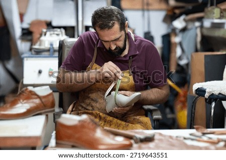 Skilled shoemaker at work measuring a leather shoe in a busy workshop