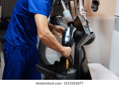 A skilled technician in blue uniform carefully polishes a prosthetic leg using specialized equipment in a workshop, showcasing precision and craftsmanship. - Powered by Shutterstock