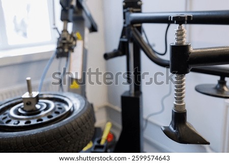 A skilled technician is precisely adjusting wheel alignment equipment in a well-lit garage. Tools and a mounted tire are prominently featured, highlighting the importance of vehicle maintenance.