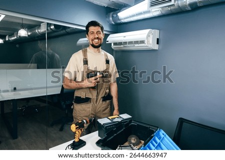 Skilled technician preparing for maintenance work in modern office space with tools at hand during daylight hours