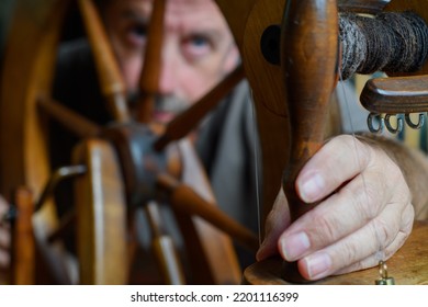 Skilled tradesman looks to repair and to intricately fettle the mechanism of an old wooden spinning wheel. Selective focus to accentuate the task of repair.  - Shutterstock ID 2201116399