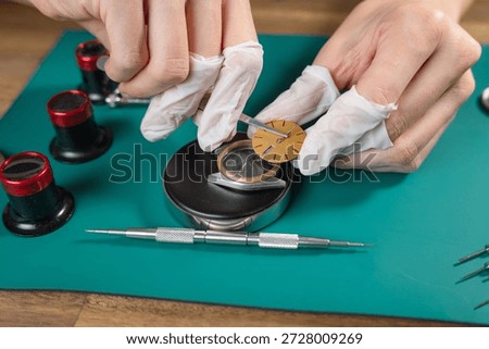A skilled watchmaker assembles a luxury mechanical watch movement using fine tools and attention to detail on a clean workbench.