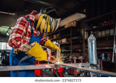 Skilled welder assembling durable pipelines for infrastructure projects while using his welding machine with great responsibility.Focus on yellow sparks coming out while he is welding a piece of metal - Powered by Shutterstock