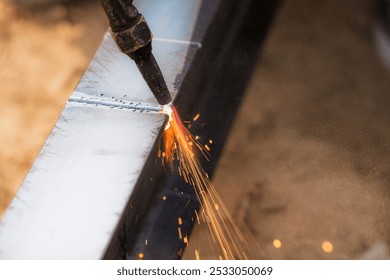 Skilled welder cuts metal with a gas torch in industrial workshop. Sparks fly during precision fabrication process. Craftsman control and expertise in metalworking. Gas torch cuts through steel. - Powered by Shutterstock