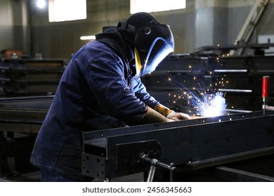 Skilled Welder in protection at Work with Sparks Flying in Industrial Workshop - Powered by Shutterstock