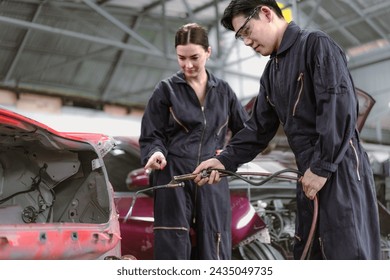 Skilled welder welding damage auto body car with blue spark at workshop. Auto mechanic in uniform working at repair garage station fixing broken vehicle. Repairman occupation in automotive maintenance - Powered by Shutterstock