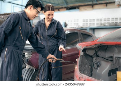 Skilled welder welding damage auto body car with blue spark at workshop. Auto mechanic in uniform working at repair garage station fixing broken vehicle. Repairman occupation in automotive maintenance - Powered by Shutterstock