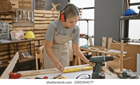 Skilled woman carpenter measuring wood in a well-equipped workshop full of tools - Powered by Shutterstock