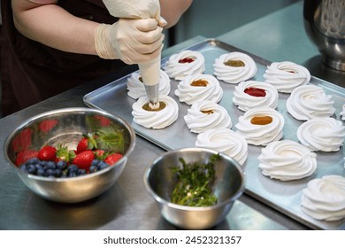 Skilled woman confectioner adding whipped cream on the top of merengue nest - Powered by Shutterstock