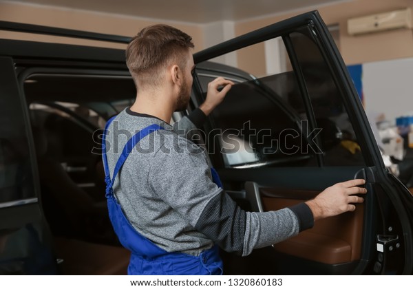 Skilled worker\
checking tinted car window in\
shop