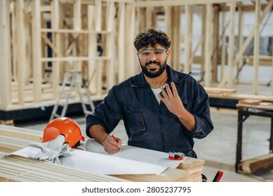 Skilled worker, front view. Portrait of a male carpenter posing in a woodworking workshop.