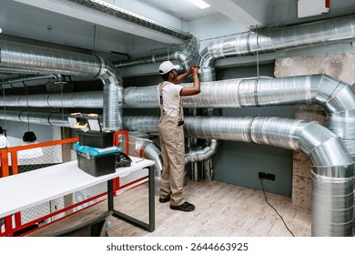 Skilled worker installing ventilation system in modern commercial building during daytime
