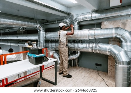 Skilled worker installing ventilation system in modern commercial building during daytime