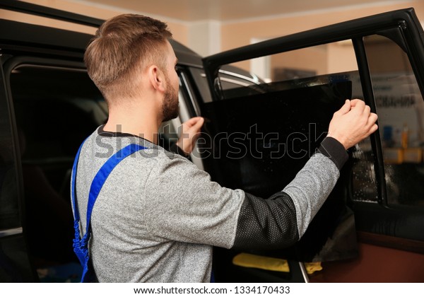 Skilled worker tinting\
car window in shop