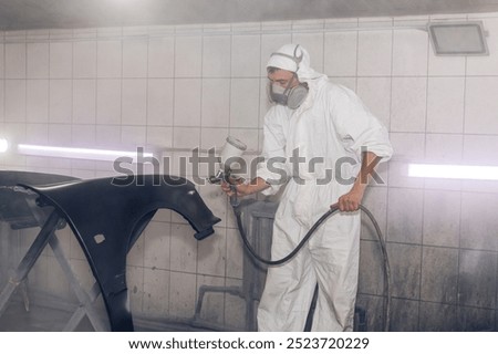 Skilled worker using spray gun to paint car body in workshop. for automotive repair, vehicle customization, or industrial craftsmanship concepts.