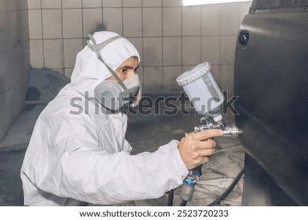 Skilled worker using spray gun to paint car body in workshop. for automotive repair, vehicle customization, or industrial craftsmanship concepts.