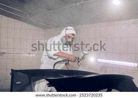Skilled worker using spray gun to paint car body in workshop. for automotive repair, vehicle customization, or industrial craftsmanship concepts.