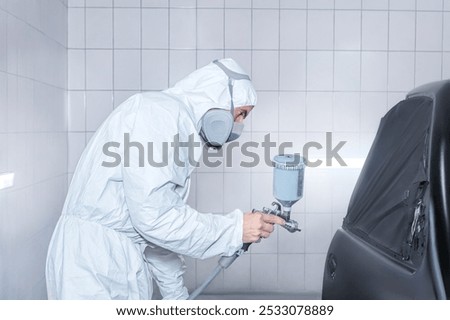 Skilled worker using spray gun to paint car body in workshop. for automotive repair, vehicle customization, or industrial craftsmanship concepts.