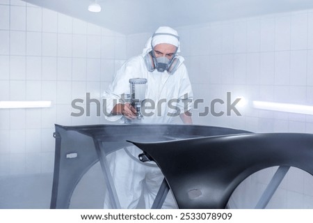 Skilled worker using spray gun to paint car body in workshop. for automotive repair, vehicle customization, or industrial craftsmanship concepts.