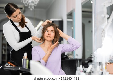 Skilled young female hairdresser offering modern hairstyling to woman client visiting professional hair salon.. - Powered by Shutterstock