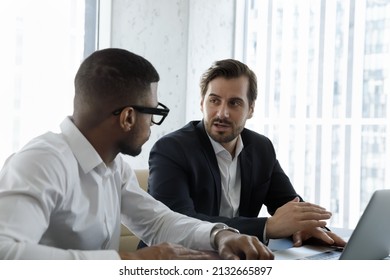 Skilled Young Male Ceo Executive Manager Boss Leader Discussing Online Project With African American Employee, Helping With Computer Apps. Focused Multiracial Partners Developing Online Strategy.