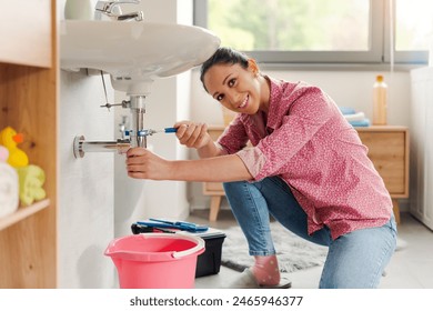 Skilled young woman fixing the bathroom sink by herself using water pump pliers, DIY concept - Powered by Shutterstock