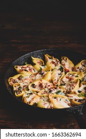 Skillet of baked jumbo shells pasta stuffed with ground beef, spinach and cheese
