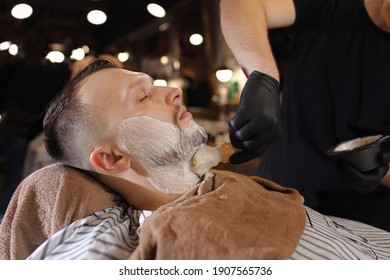 Skillful Barber. Young Man Getting An Old-fashioned Shave With Straight Razor.