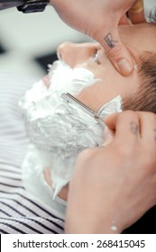 Skillful Barber. Young Man Getting An Old-fashioned Shave With Straight Razor