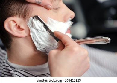 Skillful Barber. Young Man Getting An Old-fashioned Shave With Straight Razor