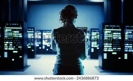 Skillful employee running code on tablet, troubleshooting and upgrading high tech workspace equipment designed to accommodate server units, networking systems and storage arrays