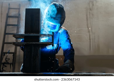 Skillful metal worker working with arc welding machine in factory while wearing safety equipment. Metalwork manufacturing and construction maintenance service by manual skill labor concept - Powered by Shutterstock