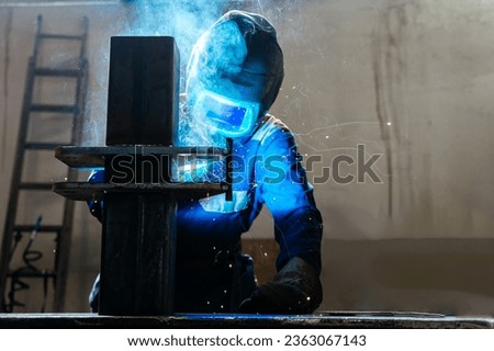 Skillful metal worker working with arc welding machine in factory while wearing safety equipment. Metalwork manufacturing and construction maintenance service by manual skill labor concept