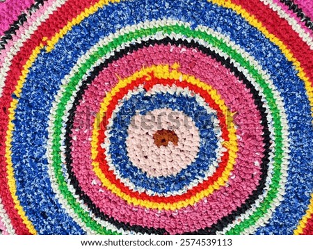 A skillfully woven circular mat features a striking array of colors and intricate patterns, ideal for decoration or functional use.
