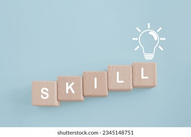 For up skilling and personal development concept. Skill training, education, learning, ability, knowledge, SKILL word   on wooden cube block with brighten lightbulb icon on grunge blue background