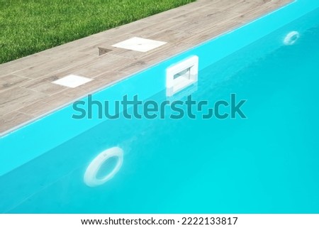 Skimmer and LED lighting in a blue pool in a country house. Clear blue water in the pool. Relax in the backyard of a country house