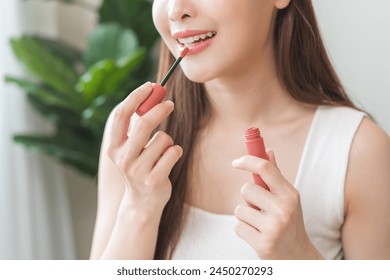 Skin care, beauty cosmetics concept, pretty asian young woman, girl make up face by applying red lipstick, lips balm on her mouth, looking at the mirror at home. Female look with natural fashion style - Powered by Shutterstock