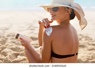 Skin Care. Beauty Woman Applying Sunscreen Cream On Tanned Shoulder.  Body Sun Protection Suncream. Bikini Hat Woman Applying Moisturizing Sunscreen Lotion On Back.