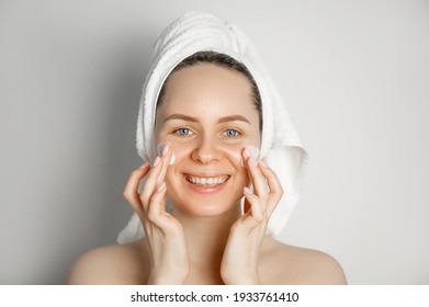 Skin care concept.Young smiling female in towel applying face cream. Taking care of young skin concept.Problem skin