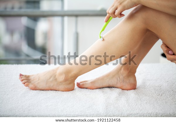 Skin care and health, fit woman shaving her legs\
with razor.