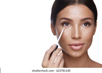 Skin Care. Portrait Of Beautiful Sexy Female With Natural Makeup Applying Corrector On Perfect Fresh Skin. Closeup Of Attractive Woman Applying Concealer With Brush. Beauty Face. High Resolution
