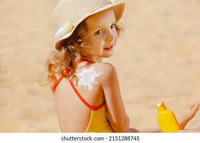 Skin care. Protection from the sun. Sunscreen for children. The Girl is Holding a Moisturizing Sunscreen in her Hands. A child with a sun-shaped suntan lotion on his back on the beach